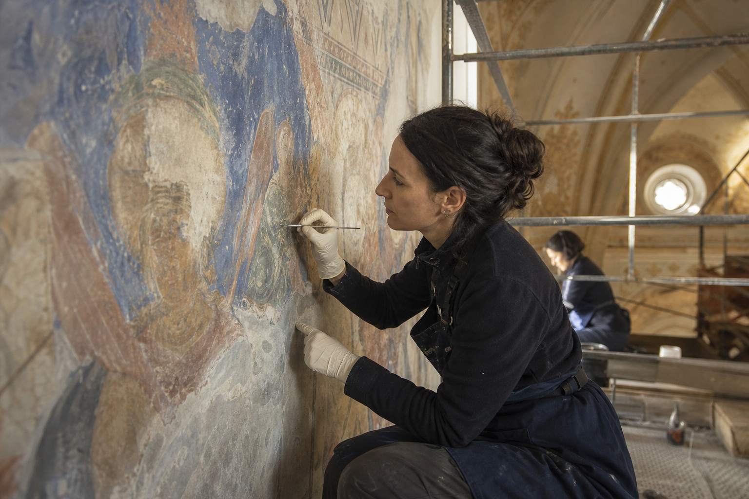 Restauratrice intervenant sur une peinture murale